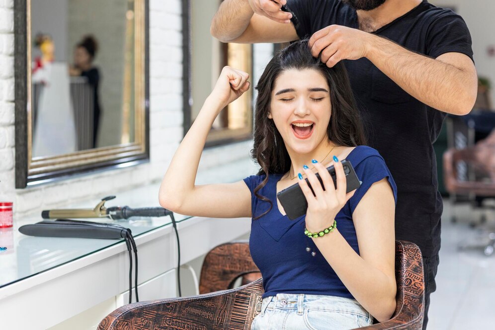 Cheerful Young Lady Looking Her Phone Squeezing Her Fist While Barber Making Her Hair High Quality Photo 144627 75986